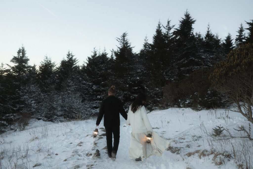 Couple bundled in coats during a snowy winter elopement on Roan Mountain with dramatic mountain views.