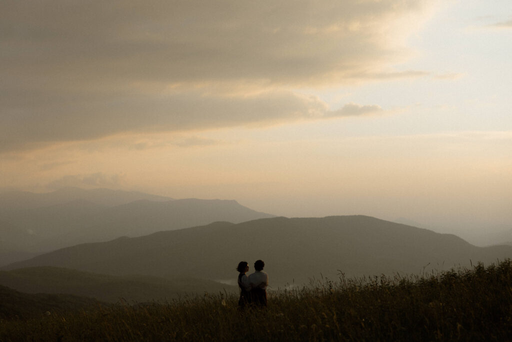 Couple during whimsical Asheville engagement session on Max Patch Western North Carolina mountain at sunset.