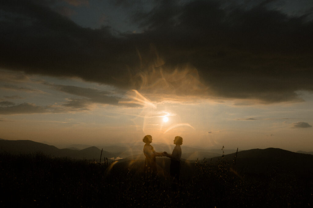 Couple during whimsical Asheville engagement session on Max Patch Western North Carolina mountain at sunset.
