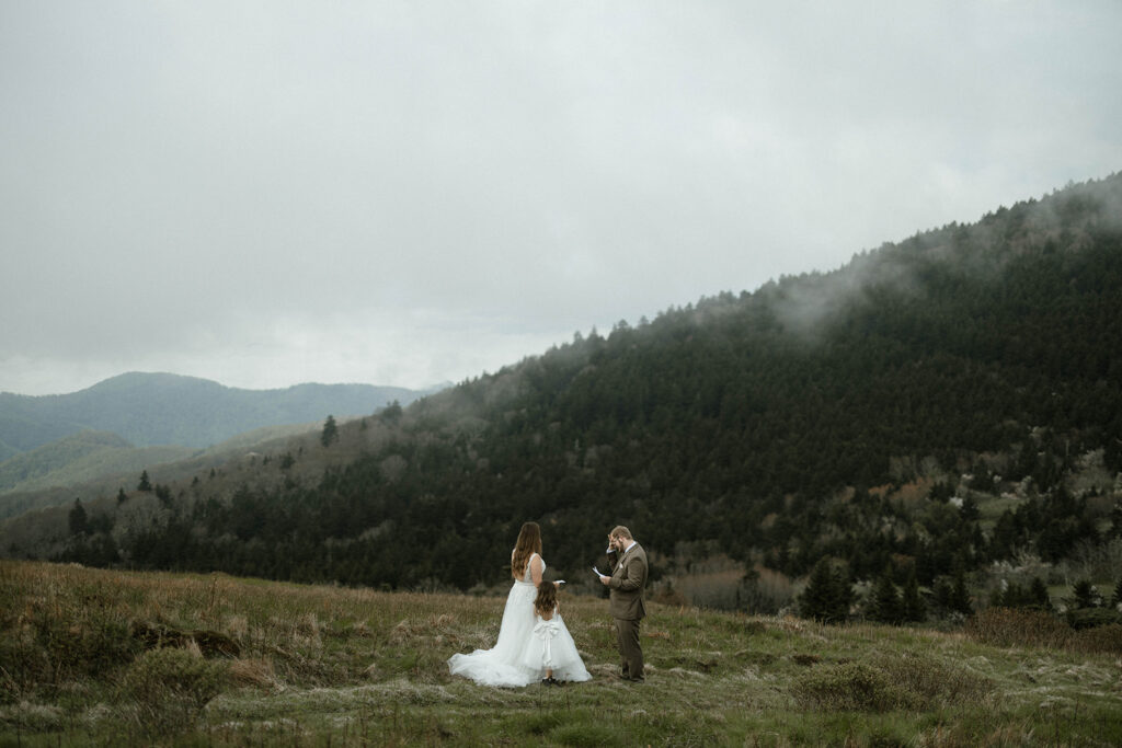 Couple standing on Roan Mountain in North Carolina surrounded by drifting fog during a moody mountain elopement near Asheville.
