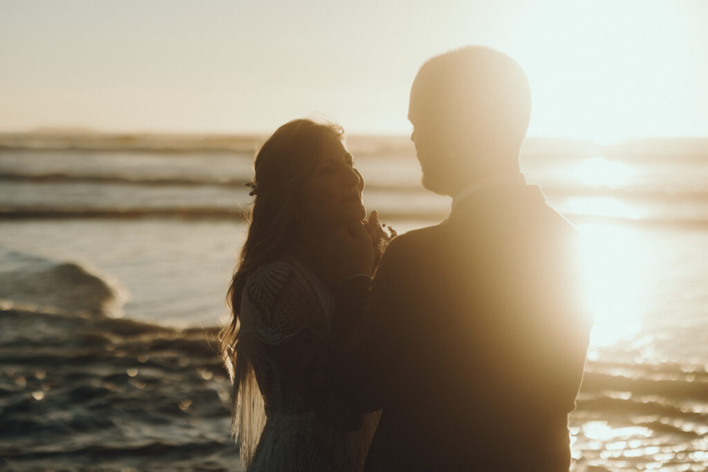 Couple walking along Ruby Beach at sunset during a summer elopement in Olympic National Park, Washington with sea stacks in the background.