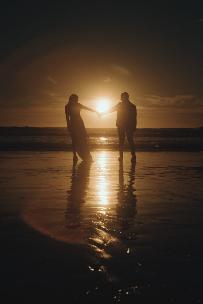 Bride and groom holding hands on Ruby Beach at golden hour during a summer Olympic National Park elopement with dramatic sea stacks and warm coastal light.