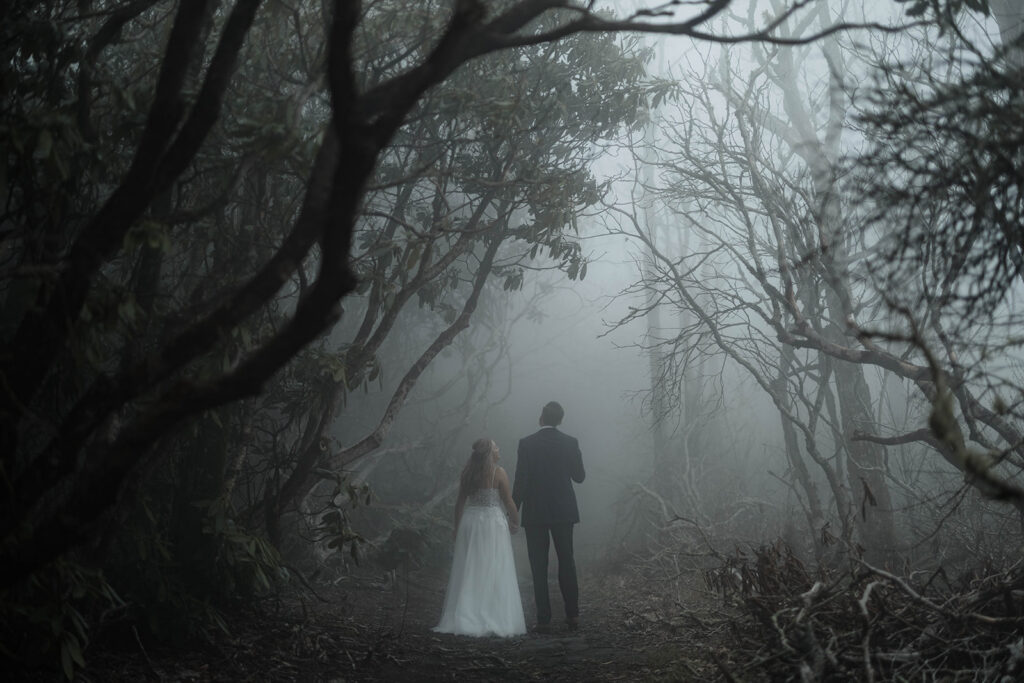 Couple walking along a misty mountain trail in Nantahala National Forest during a moody forest elopement.