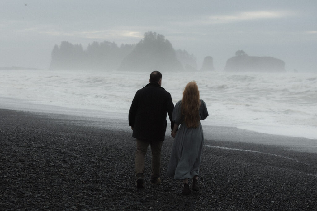 Newly married couple embracing on Rialto Beach during their Olympic National Park elopement with fog rolling in over the Pacific Ocean.