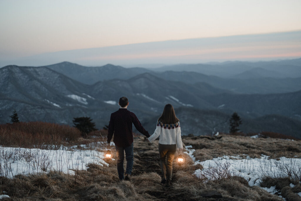 Couple bundled in coats during a snowy winter elopement on Roan Mountain with dramatic mountain views.