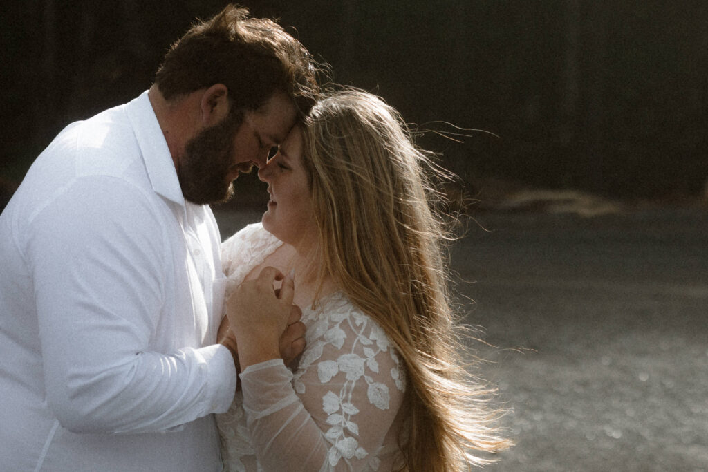 Romantic elopement portrait on Rialto Beach featuring iconic Olympic National Park sea stacks and moody coastal fog.