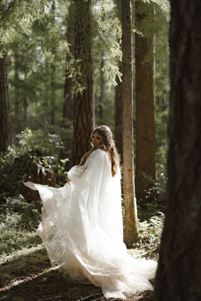Bride and groom embracing along the shoreline of Lake Cushman with evergreen forests and mountain reflections in Olympic National Park, Washington.