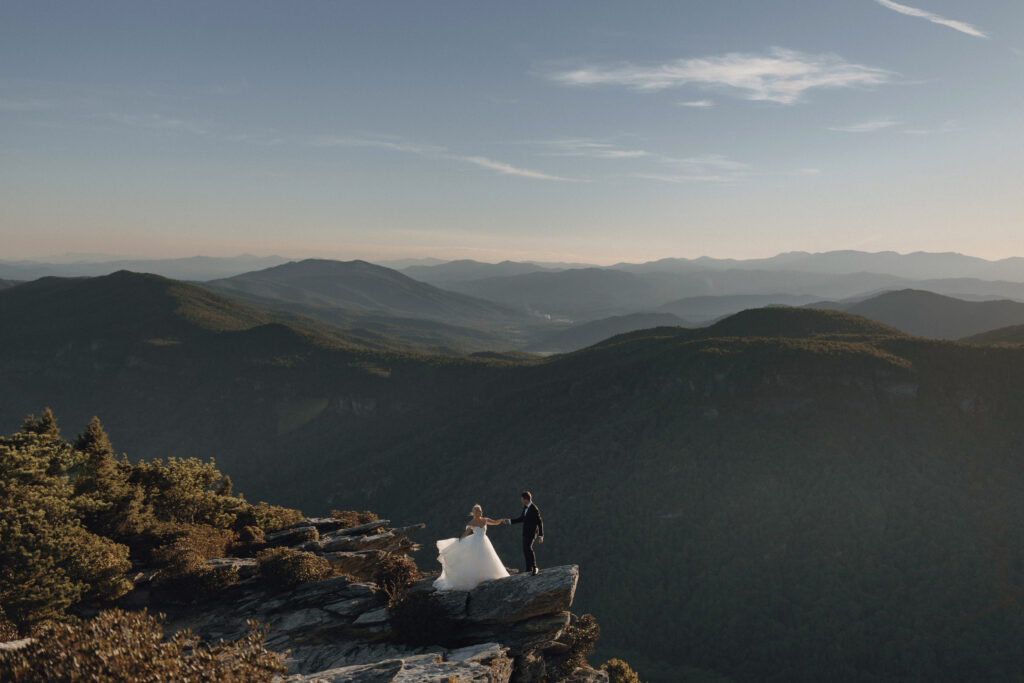 Couple embracing on a windy mountain overlook during their Blue Ridge Parkway elopement in North Carolina