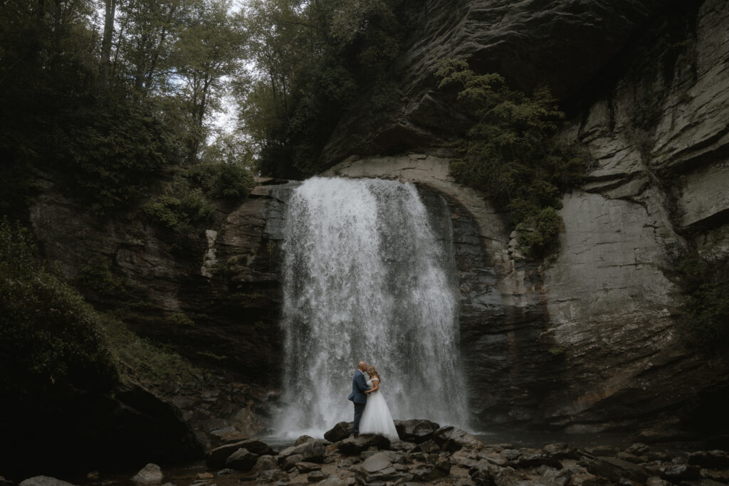 bride and groom embrace at Asheville elopement in front of looking glass falls
