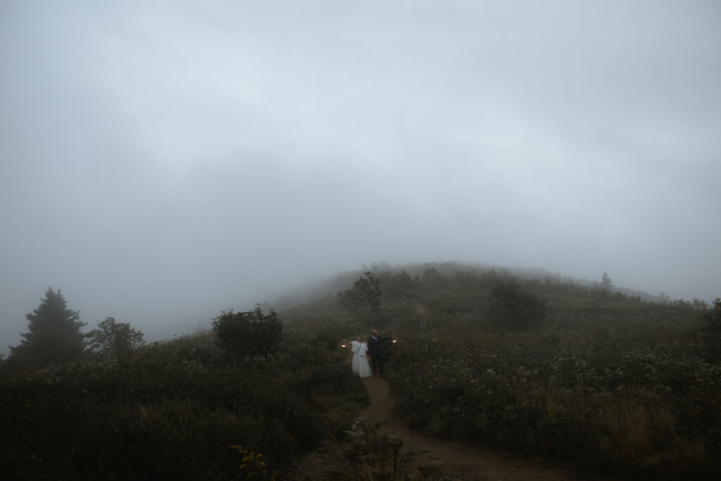 Couple embracing on the Blue Ridge Parkway in Asheville, North Carolina, surrounded by mist and moody mountain fog.