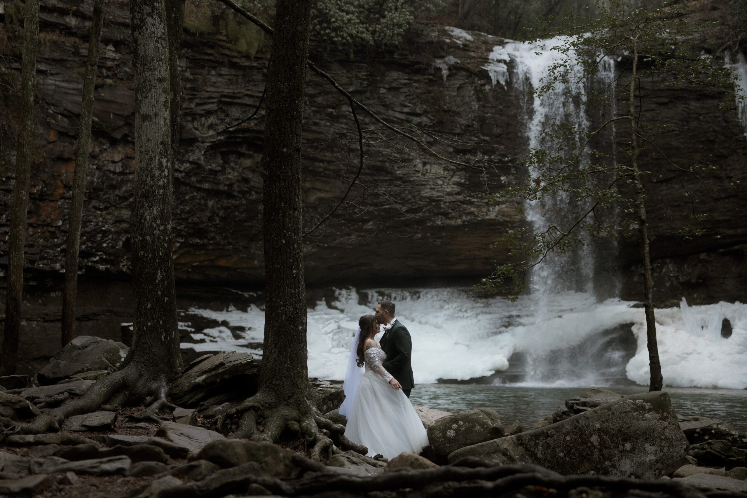 Bride and groom standing in front of a frozen waterfall during a winter elopement at Cloudland Canyon State Park